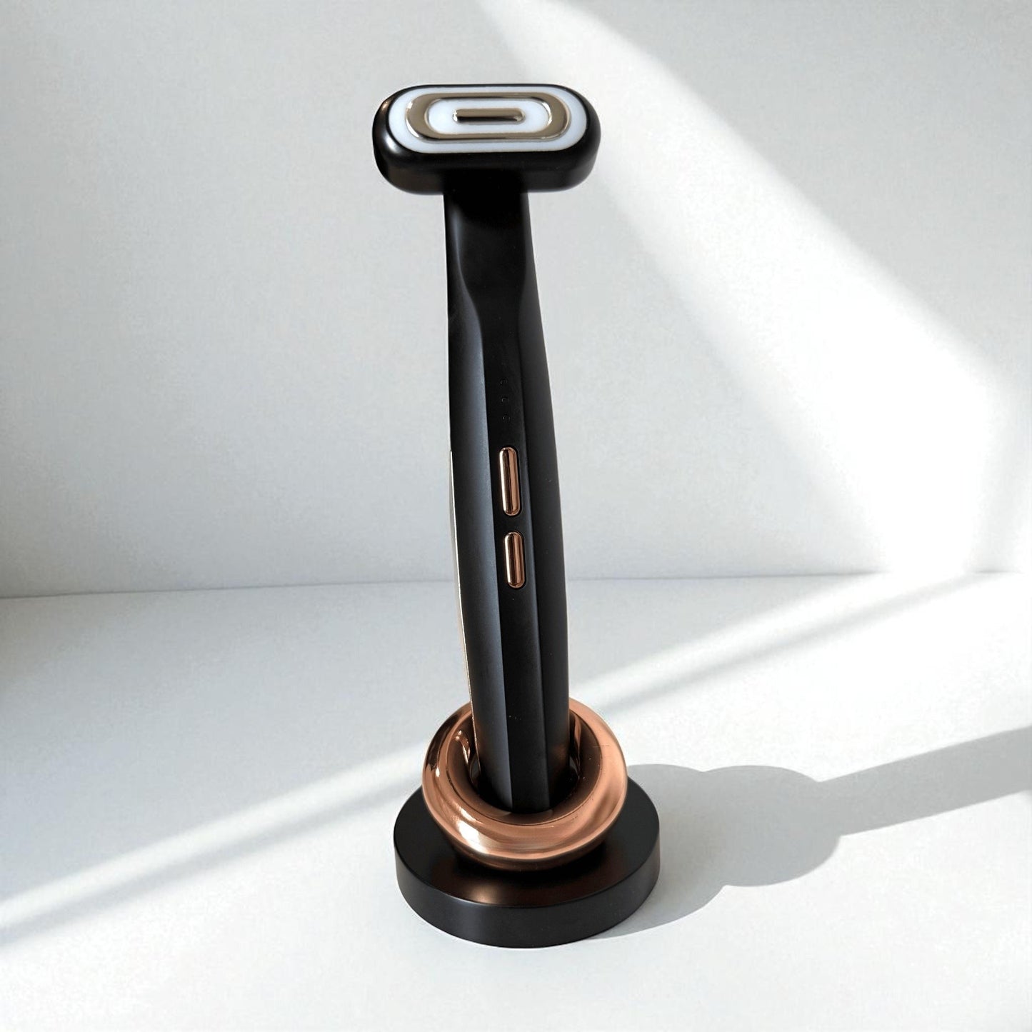 Black anti-aging light therapy face wand, standing on a minimalistic white background.