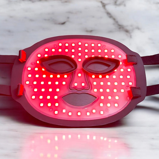 Red light therapy mask for face standing lit up.