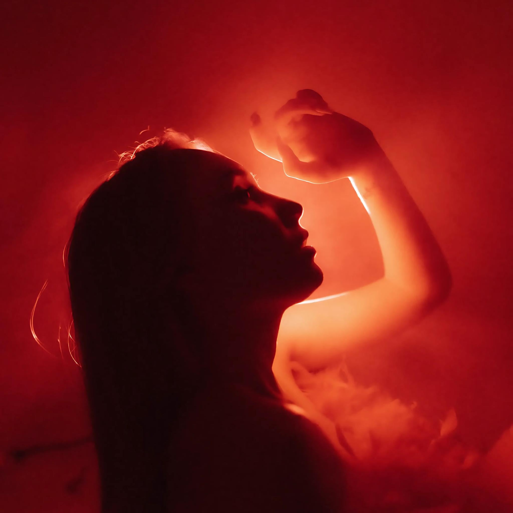 A young woman using red light therapy on her face and skin.