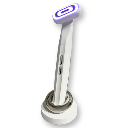 Purple light therapy beauty wand massager standing on a charging dock, with a white background.